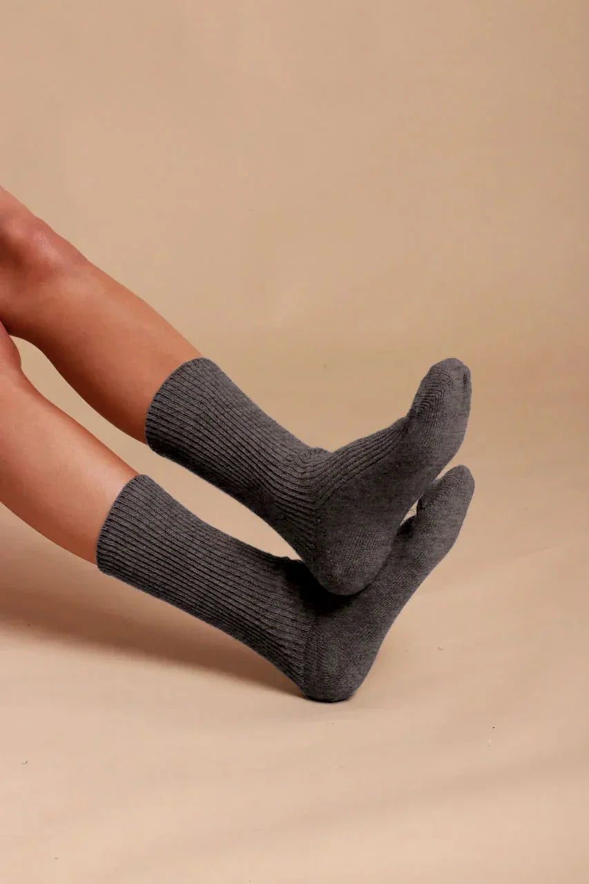 Person wearing gray organic cotton crew socks for sensitive skin on beige background