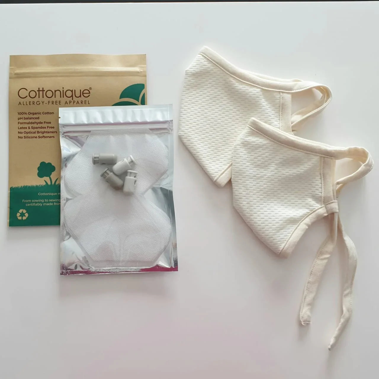 Cottonique hypoallergenic face masks, organic cotton filters, and packaging on white surface