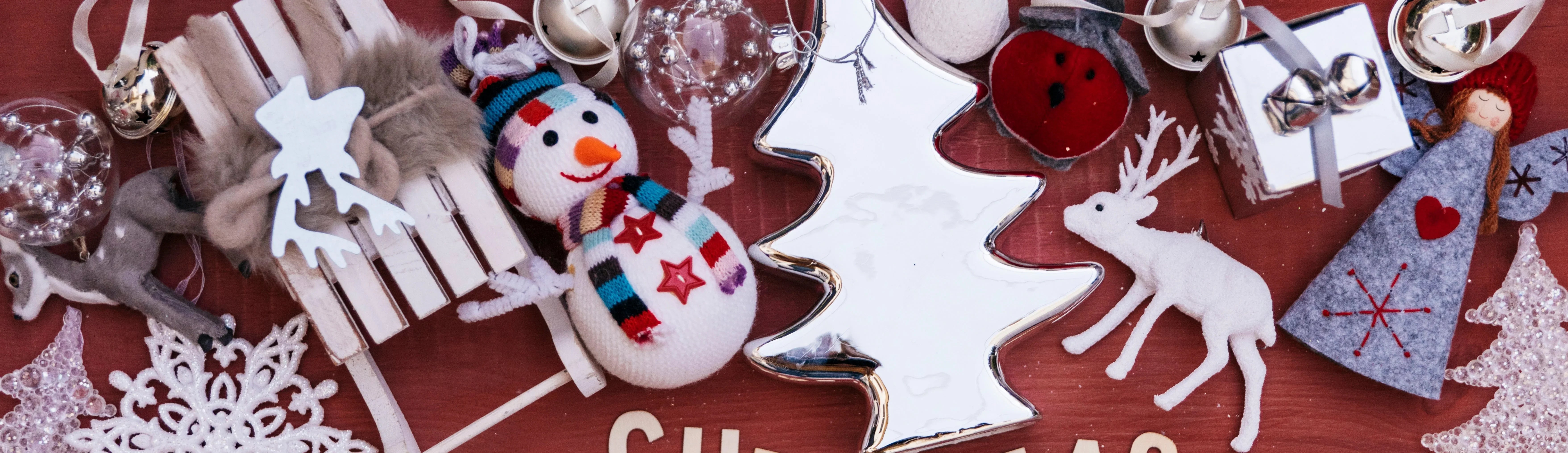 Christmas ornaments on red background with plush snowman, reindeer, silver tree, and gift box