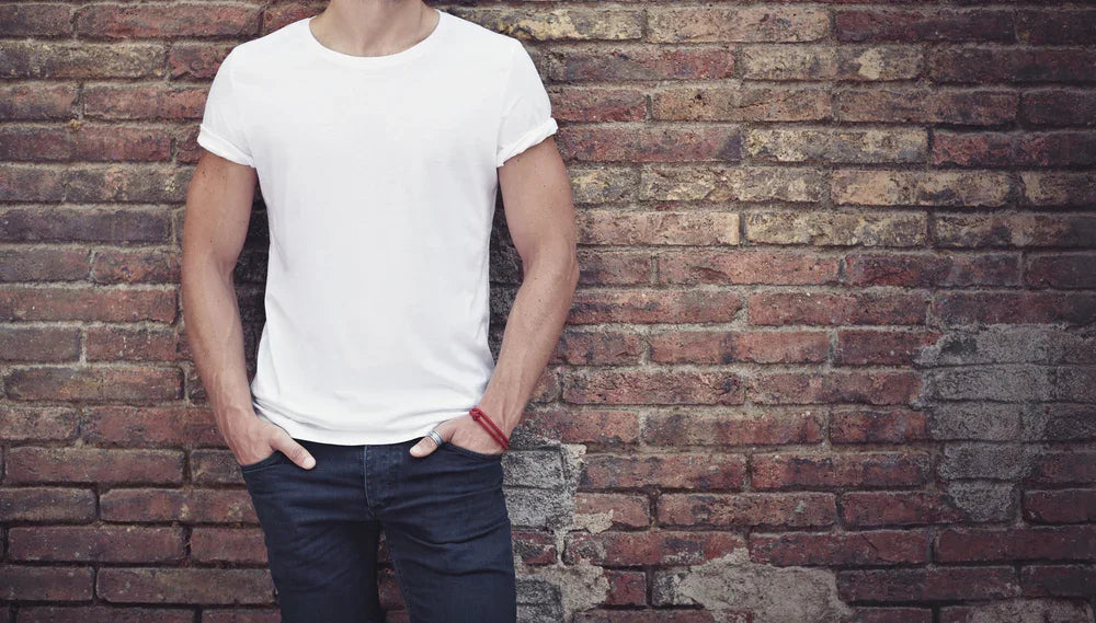 Man wearing allergy-free cotton t-shirt and jeans standing by brick wall, hypoallergenic apparel