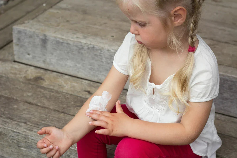 Young girl in white shirt applying cream to her arm, relief for sensitive skin or eczema