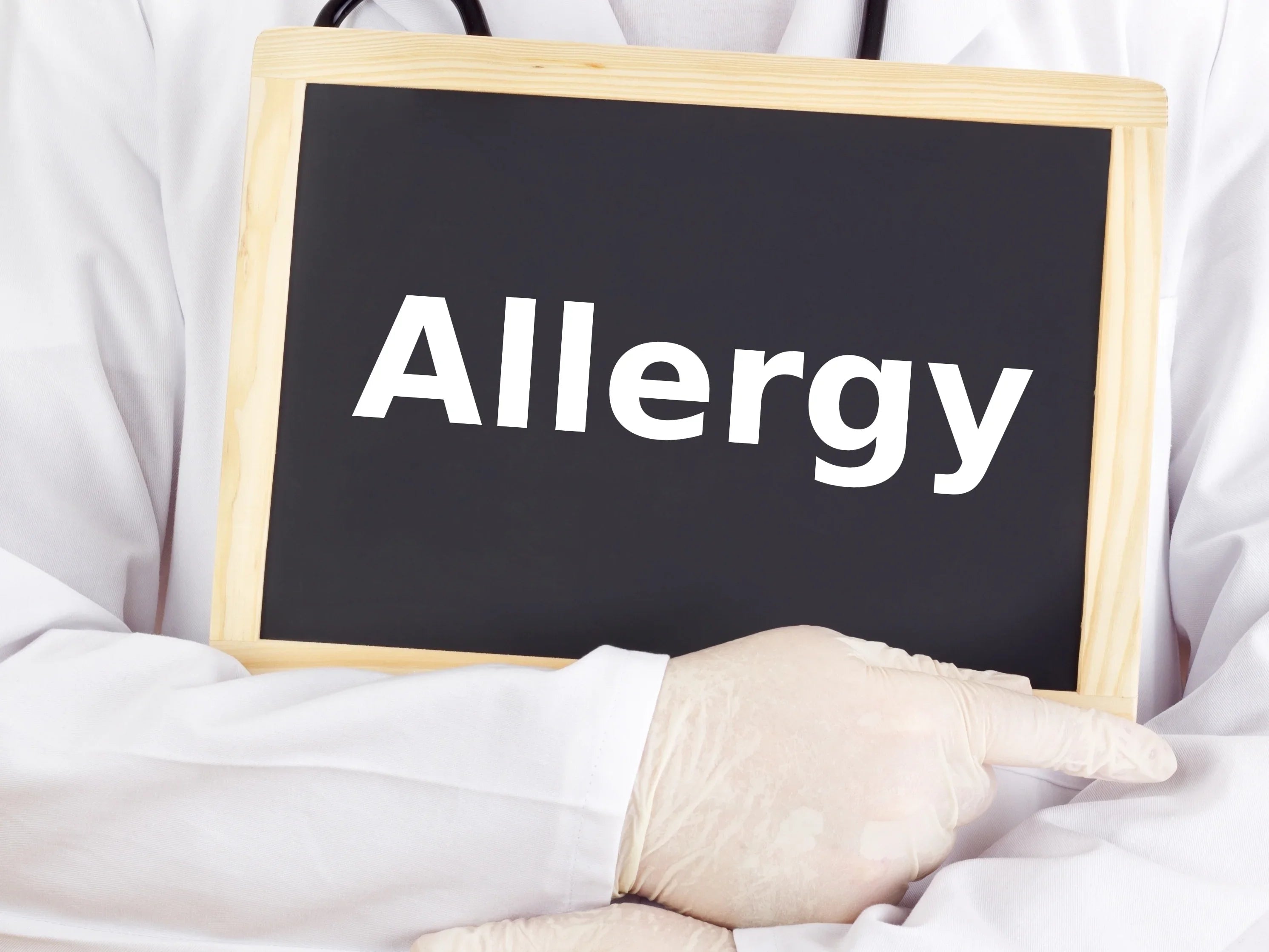 Doctor in white coat holding sign with word allergy, latex-free medical gloves visible