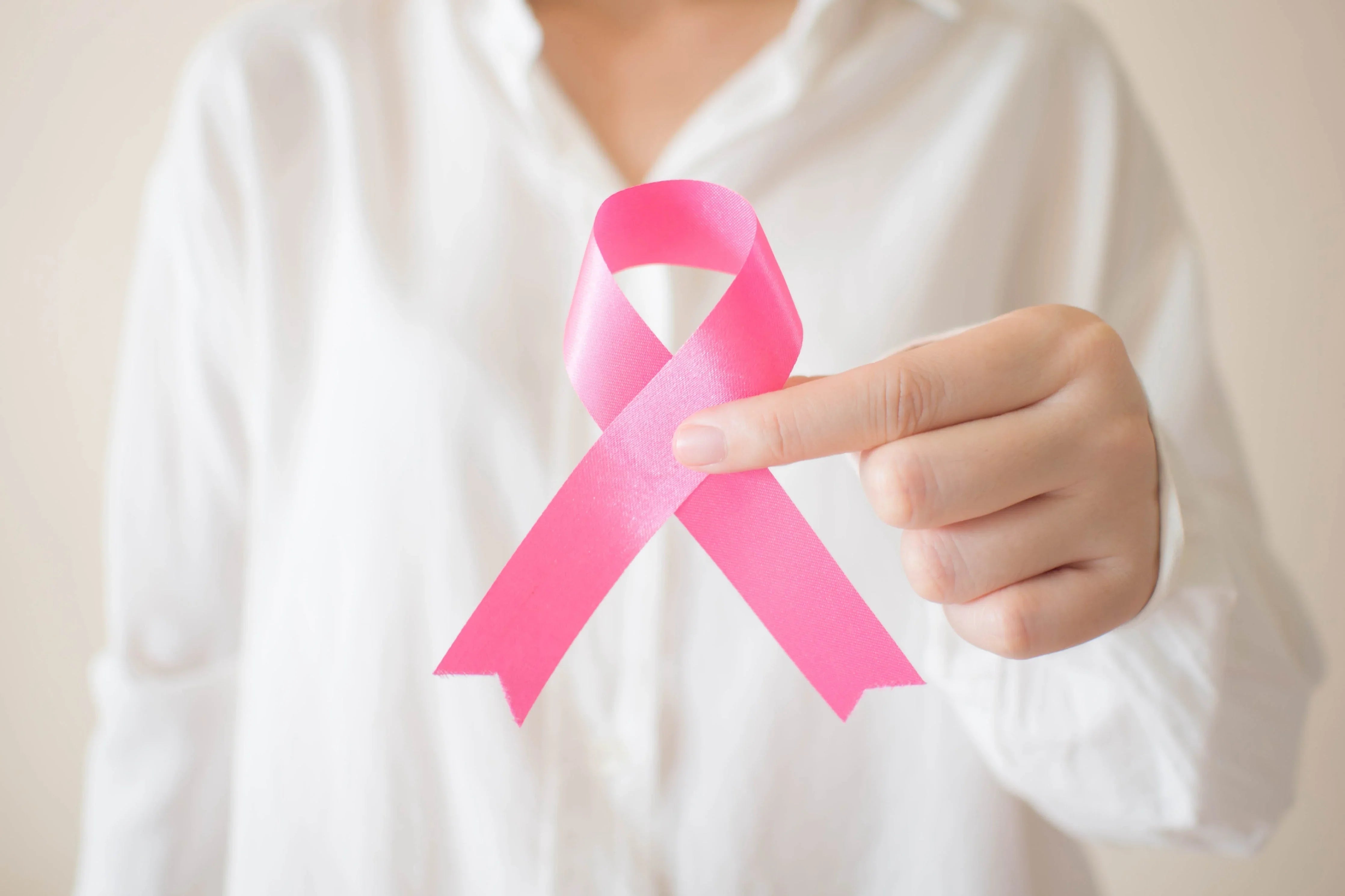 Person in white shirt holding pink awareness ribbon for sensitive skin support