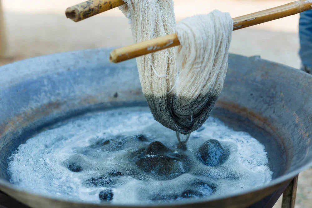 Natural cotton yarn being hand-dyed in a large metal basin for allergy-free apparel.