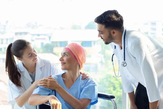 Patient in blue hospital gown and pink headscarf supported by medical staff, allergy-free clothing care