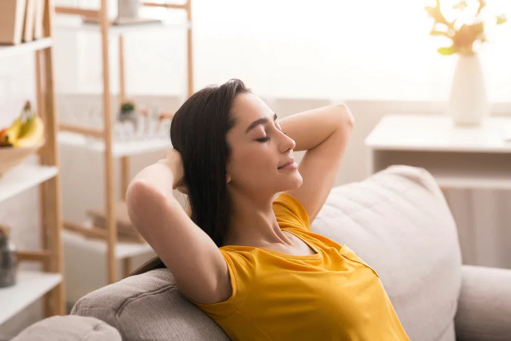 Woman relaxing on a sofa in a bright room wearing a soft yellow cotton shirt