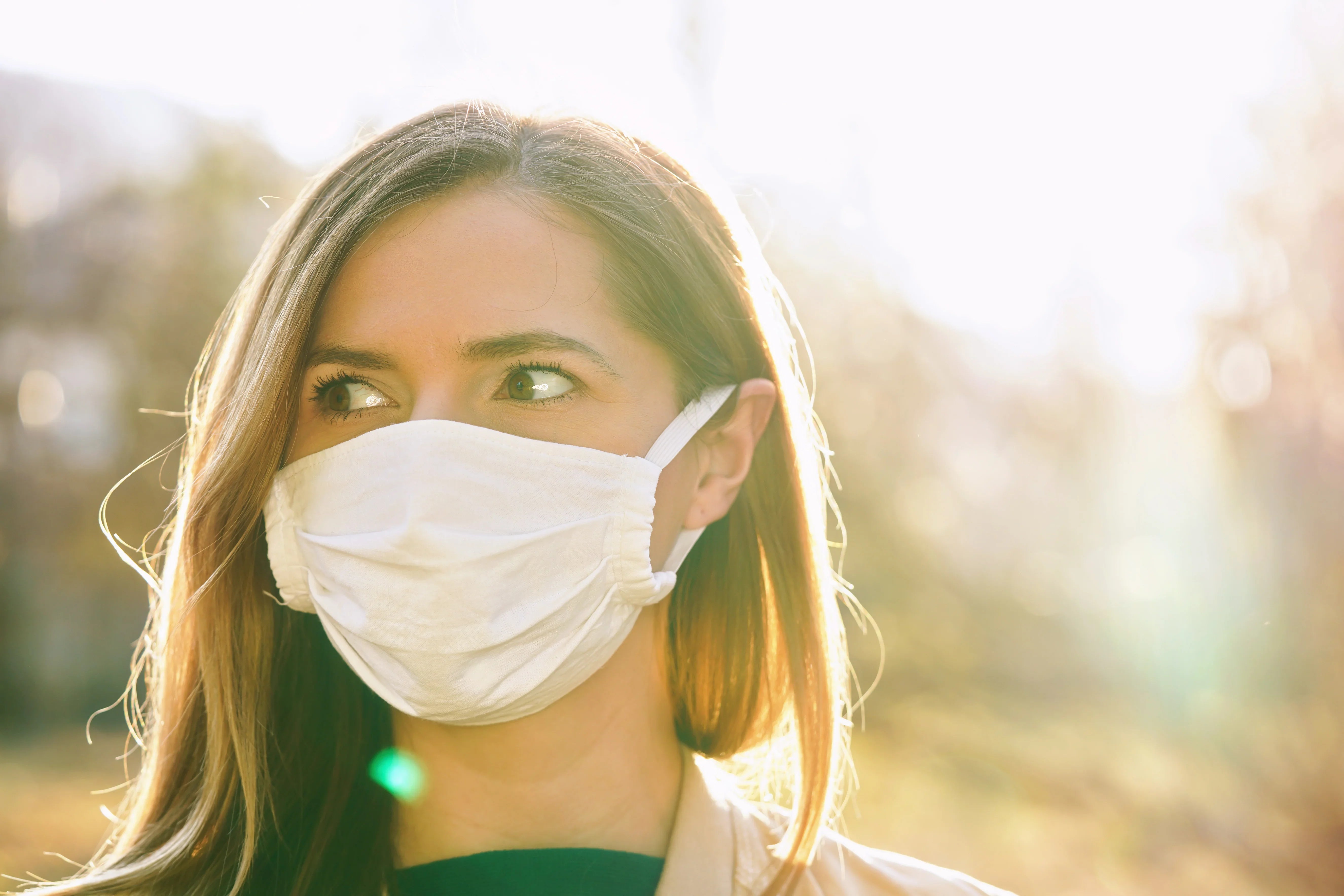 Woman outdoors wearing a hypoallergenic cotton face mask, sunlight in background