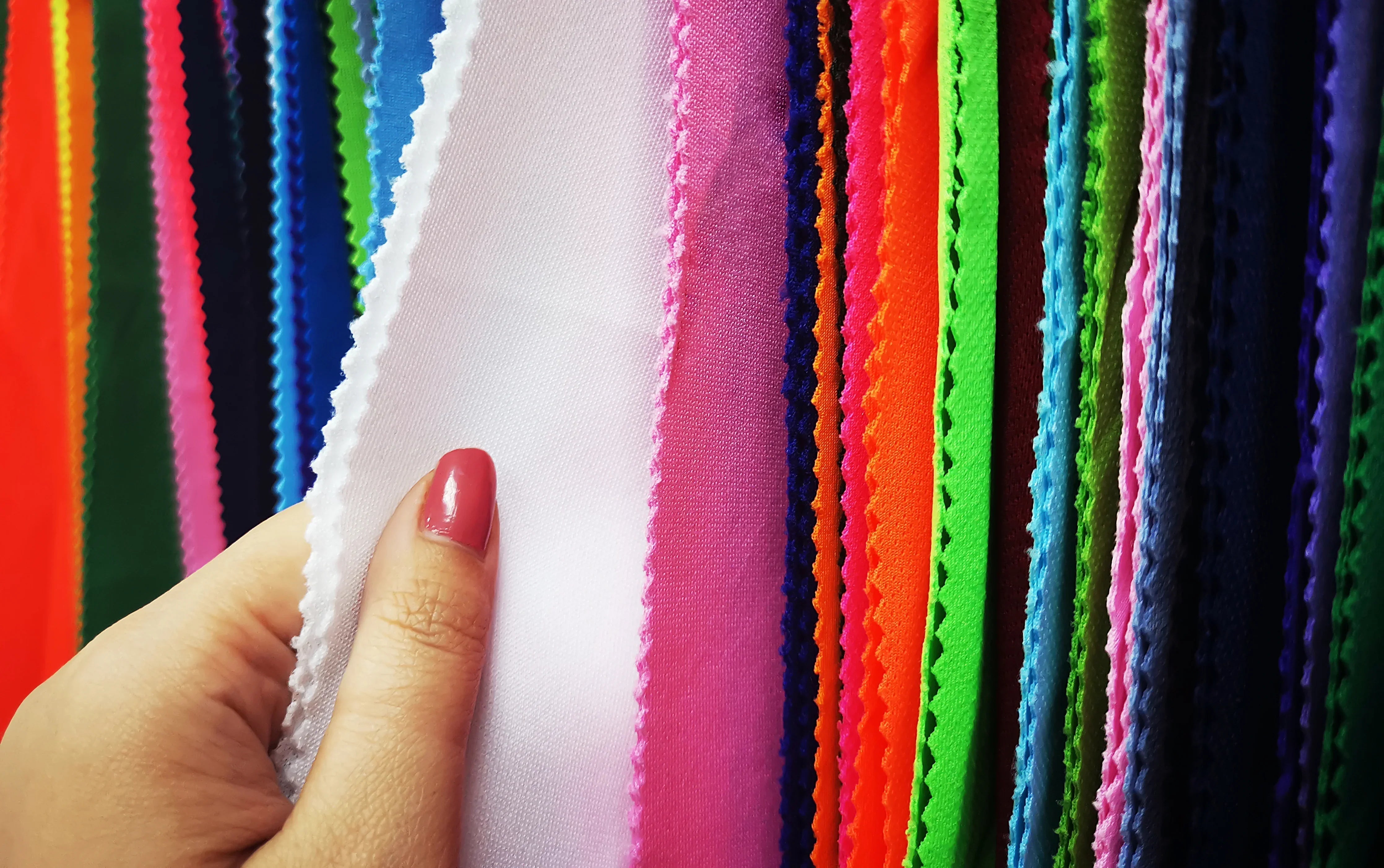 Hand touching colorful hypoallergenic cotton fabric swatches for allergy-free apparel