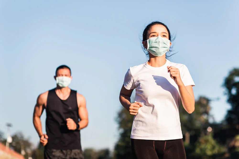 Man and woman jogging outdoors in allergy-free cotton apparel, wearing face masks