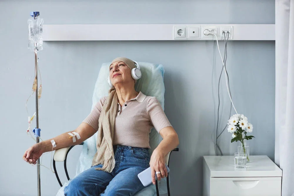 Woman with headscarf relaxing during IV therapy, wearing headphones and soft cotton top
