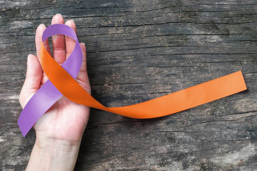 Hand holding orange and purple awareness ribbon on wooden background, hypoallergenic support