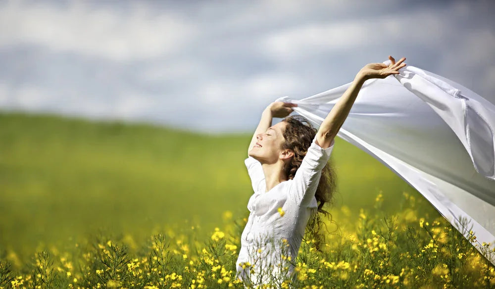 Woman in white allergy-free apparel enjoying outdoors in a field of yellow flowers