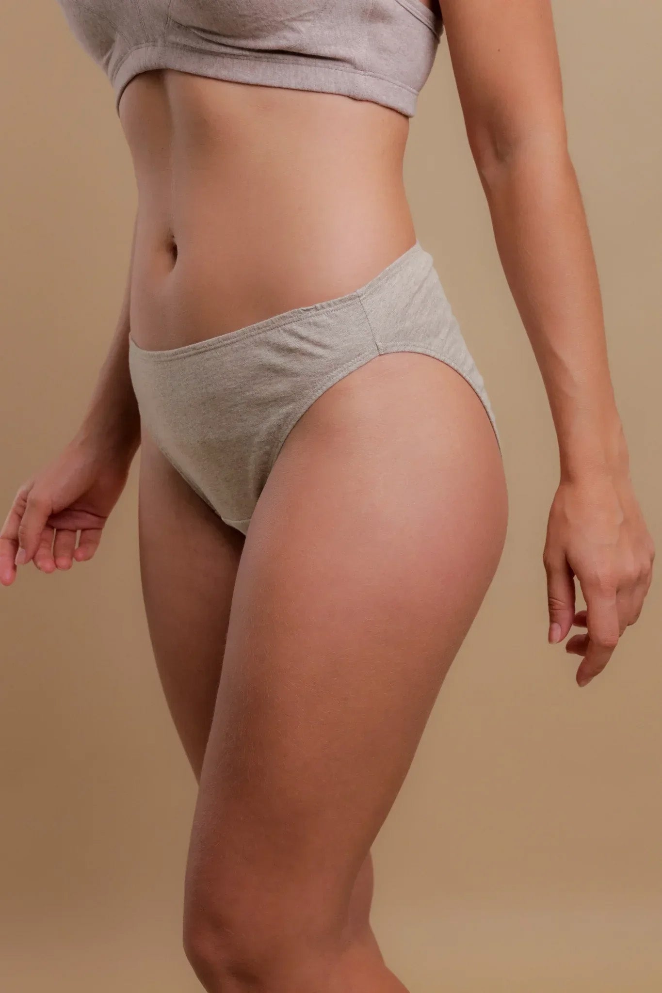 Woman wearing allergy-free cotton underwear and bra by Cottonique on neutral background