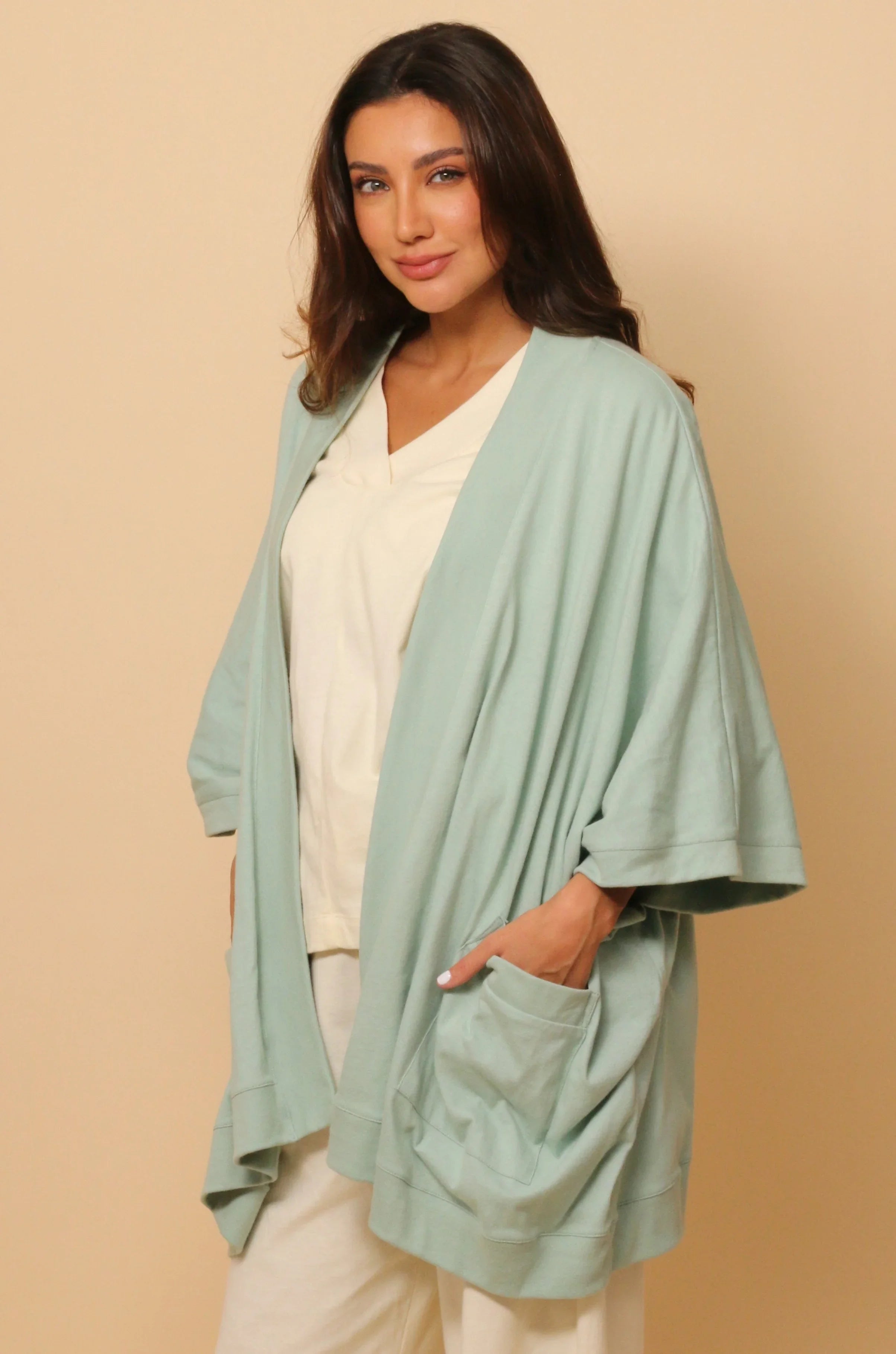 Woman wearing a light blue organic cotton cardigan over a cream shirt and pants