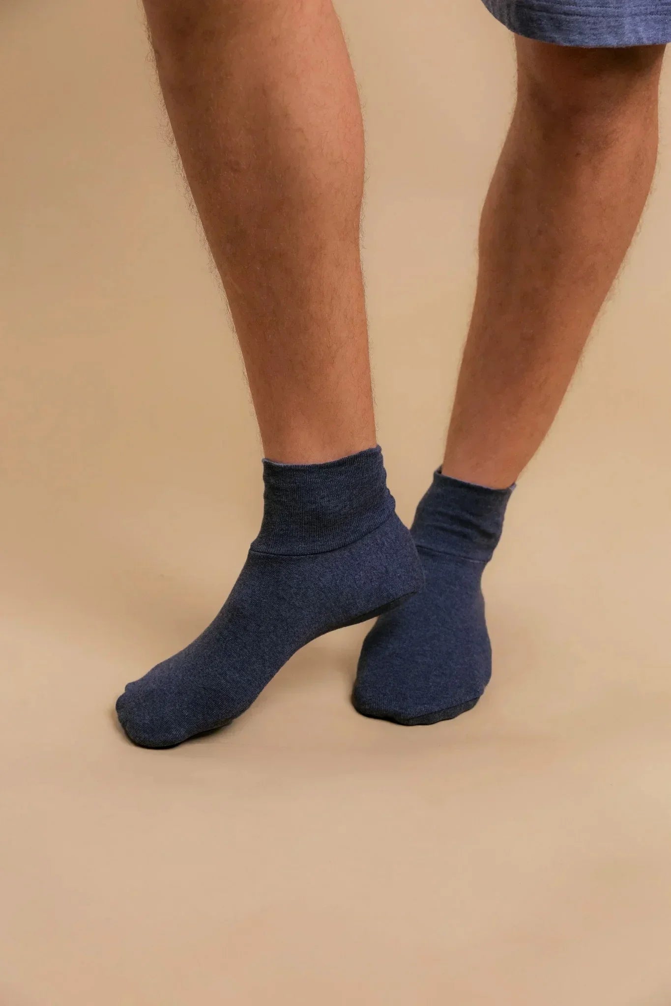 Person wearing blue hypoallergenic cotton socks by Cottonique on beige background