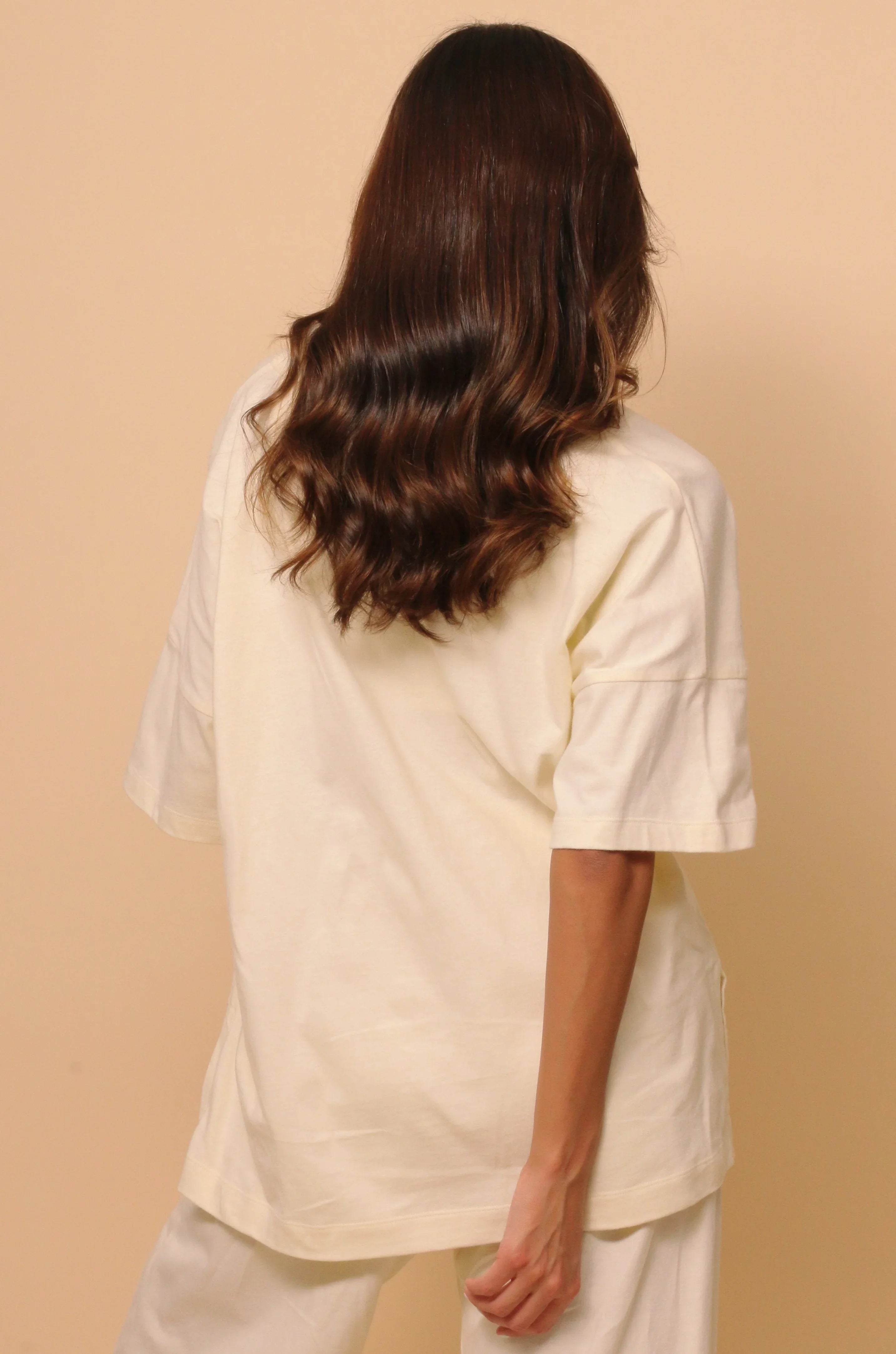 Back view of woman wearing Cottonique hypoallergenic cream short sleeve shirt and pants