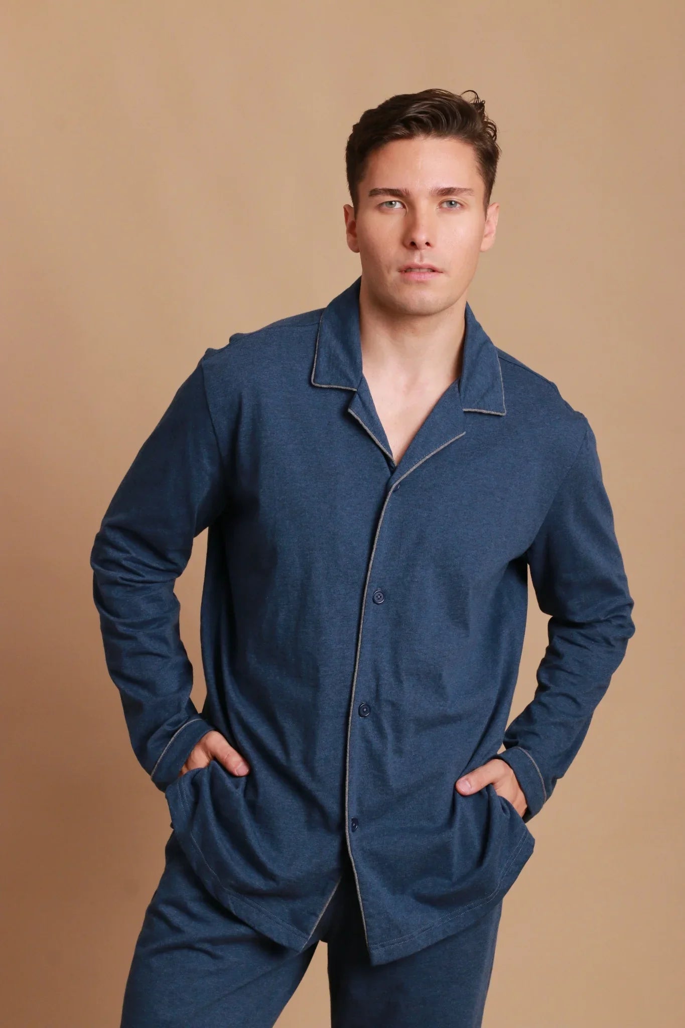 Man wearing blue hypoallergenic Cottonique loungewear set against beige background