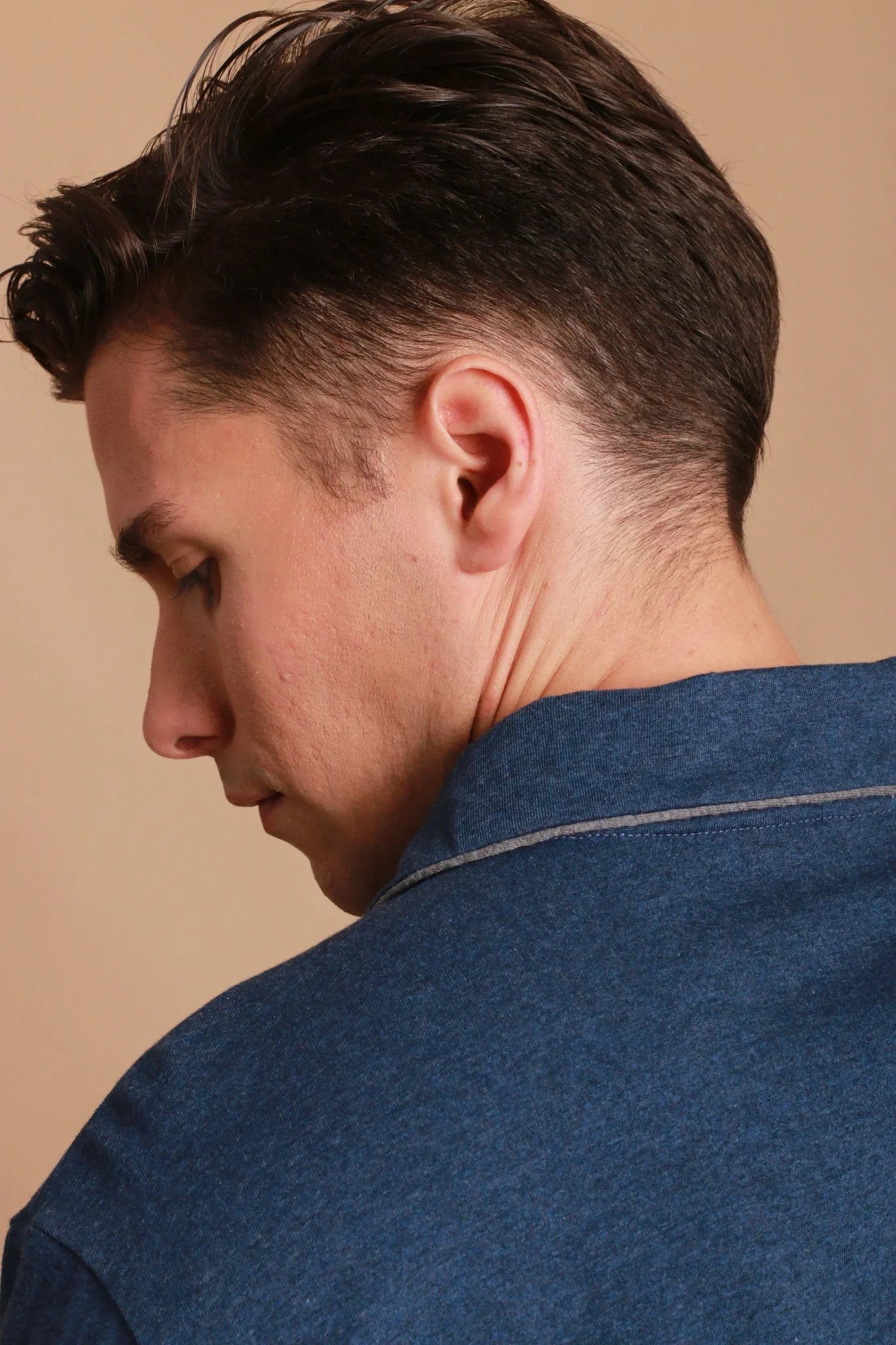 Man in blue hypoallergenic Cottonique shirt, close-up side profile, beige background