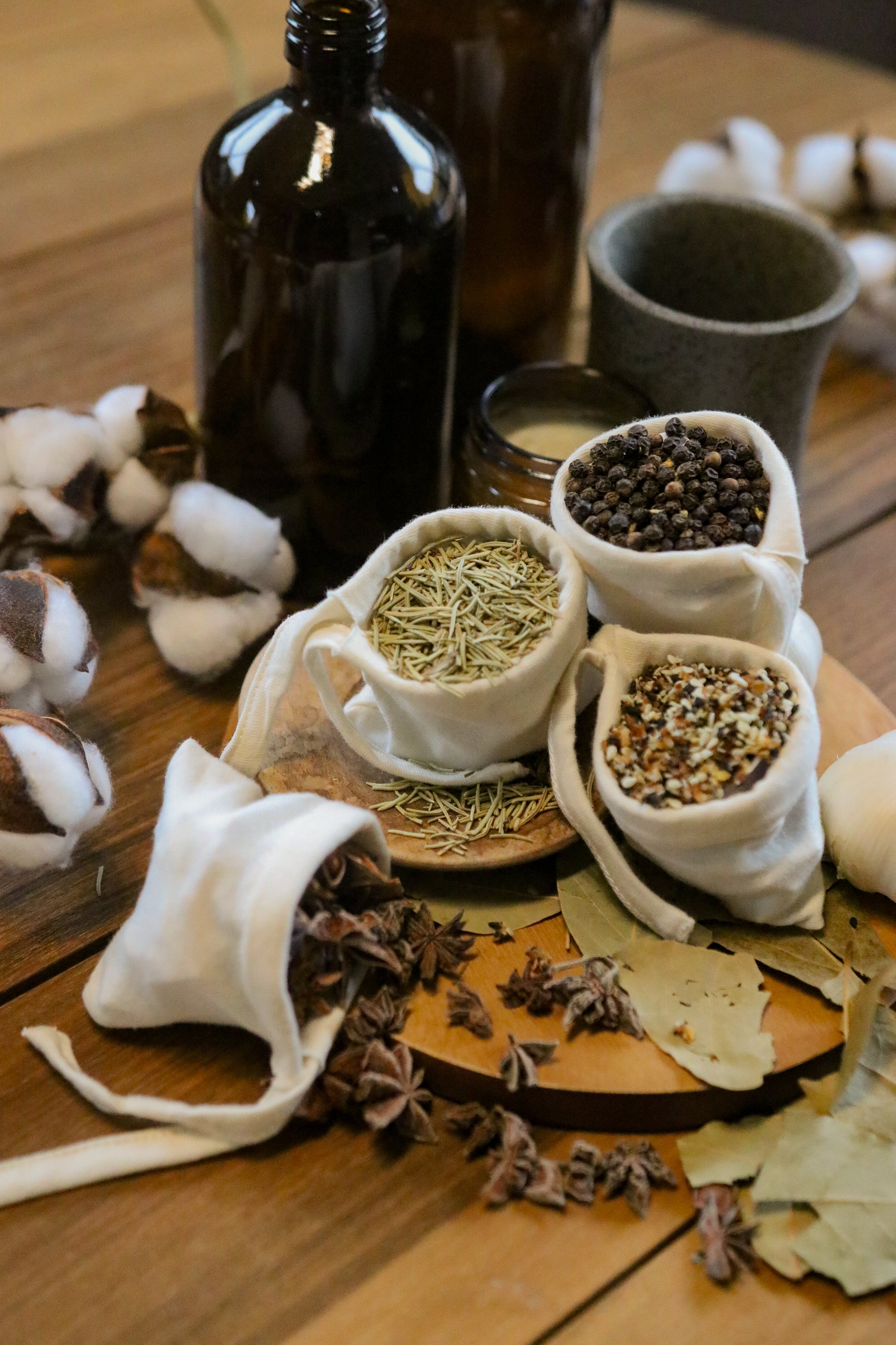 Organic cotton tea bags with herbs and spices, cotton plant, and eco-friendly packaging on wood table