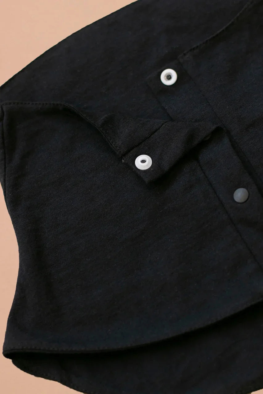 Black organic cotton shirt with white snap buttons, hypoallergenic clothing detail