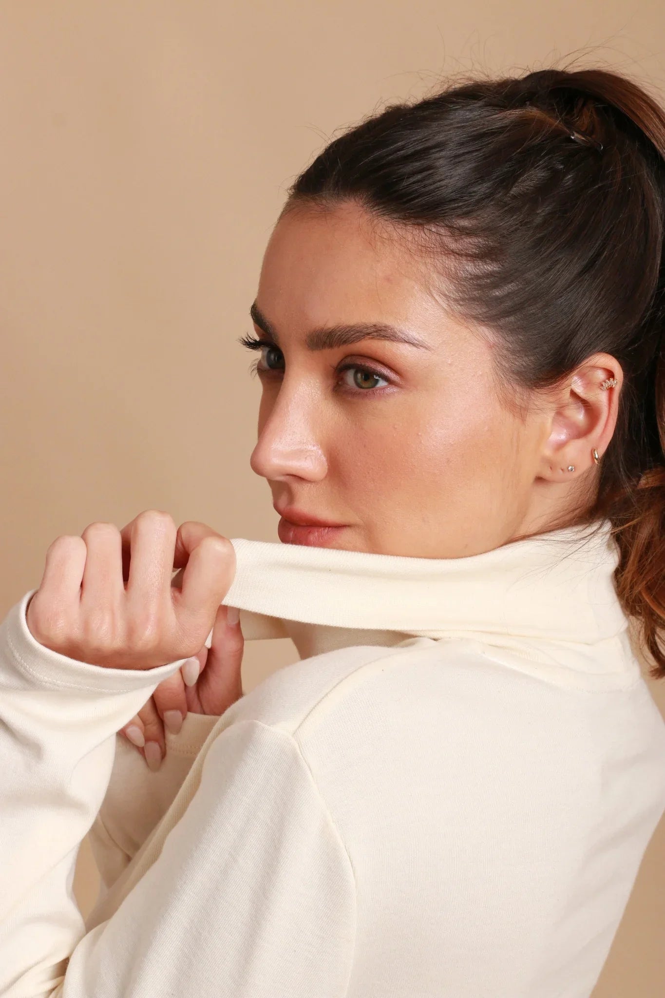 Woman wearing cream organic cotton turtleneck shirt for sensitive skin