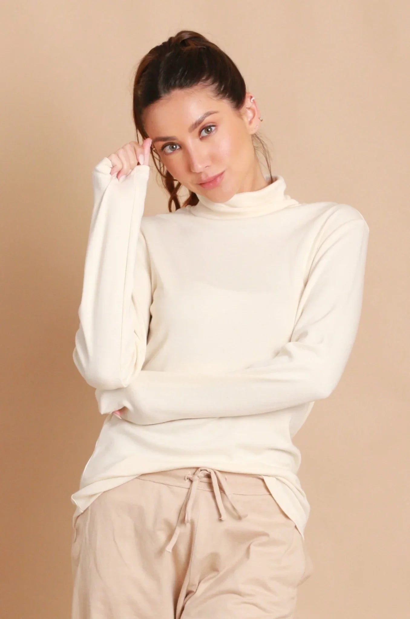 Woman wearing a long-sleeve ivory turtleneck and beige organic cotton pants