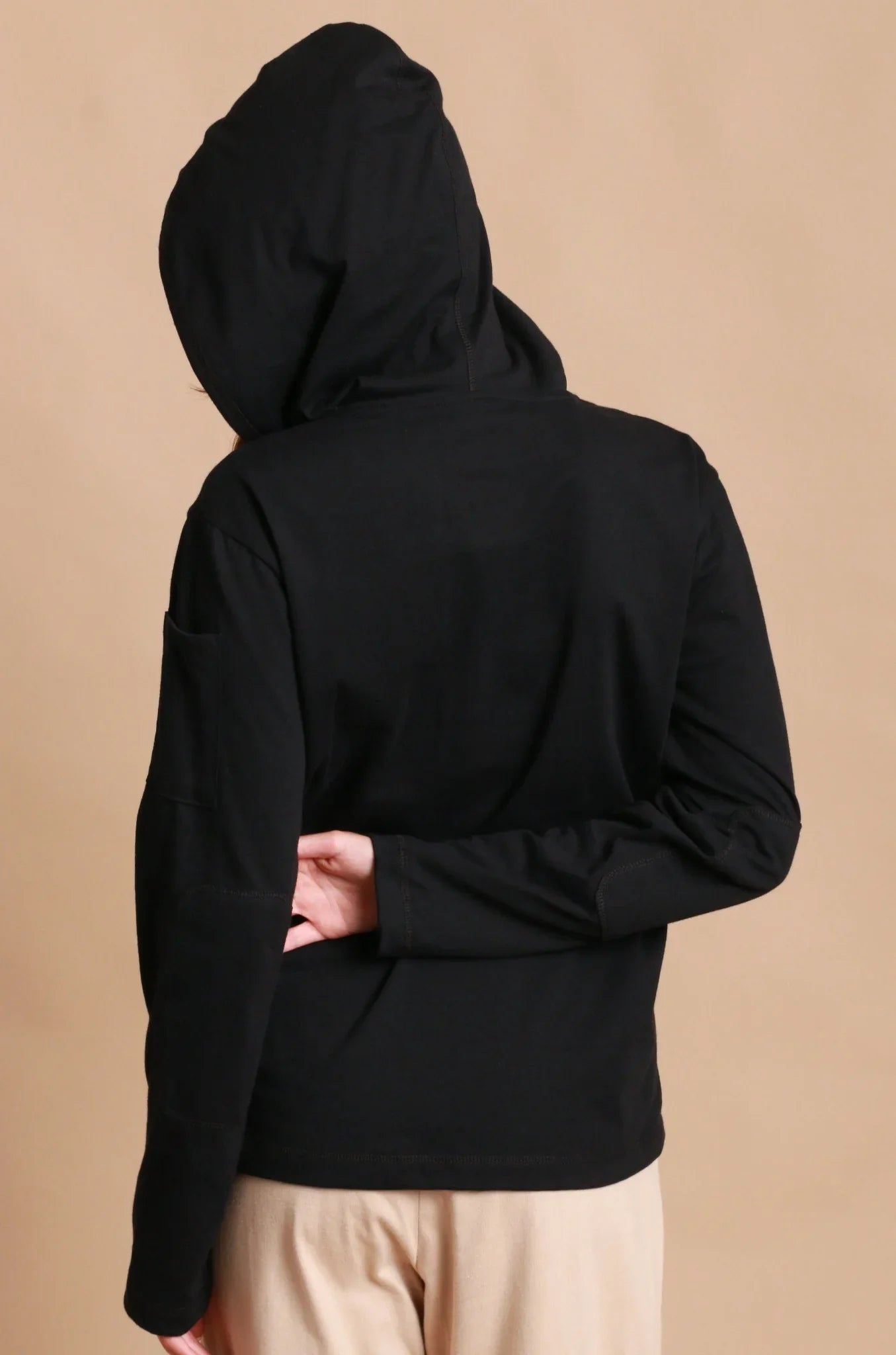 Back view of person wearing black hypoallergenic cotton hoodie and beige pants