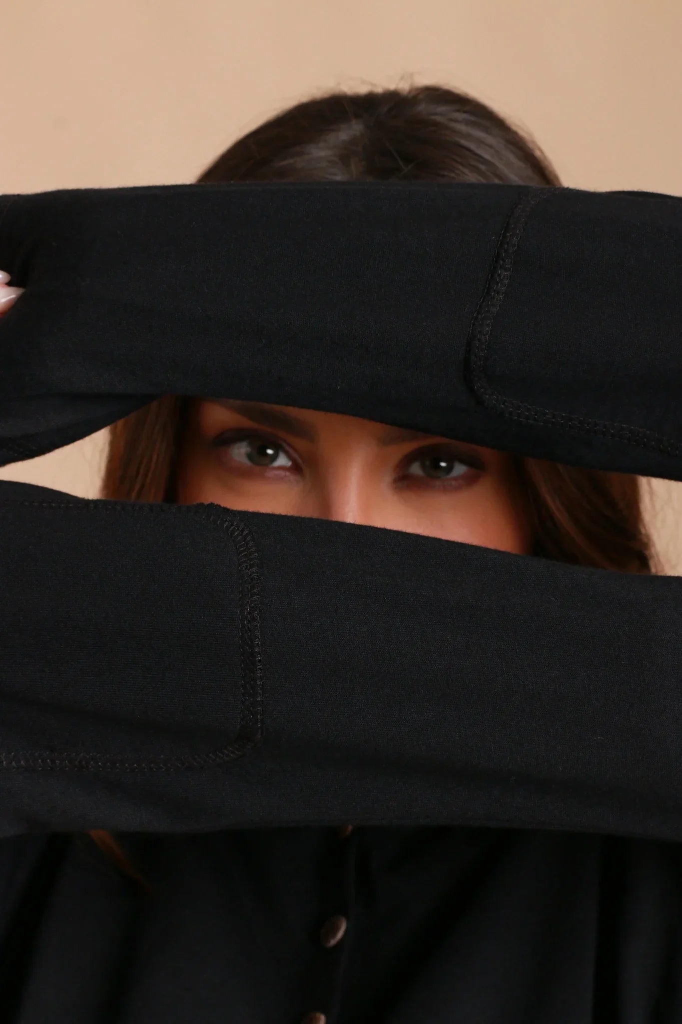 Woman in black hypoallergenic Cottonique apparel, showing eyes between crossed sleeves