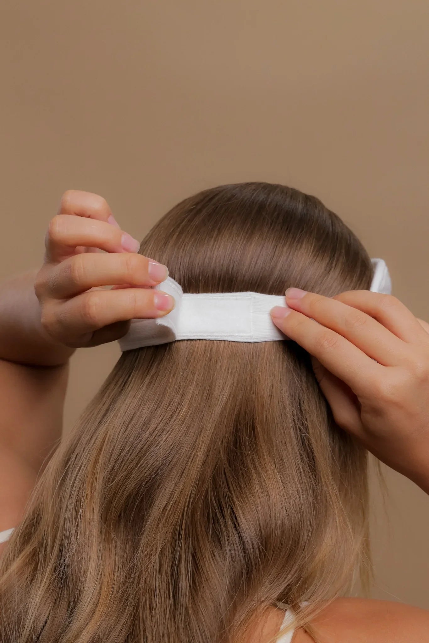 Person adjusting white hypoallergenic cotton headband on long hair, Cottonique apparel