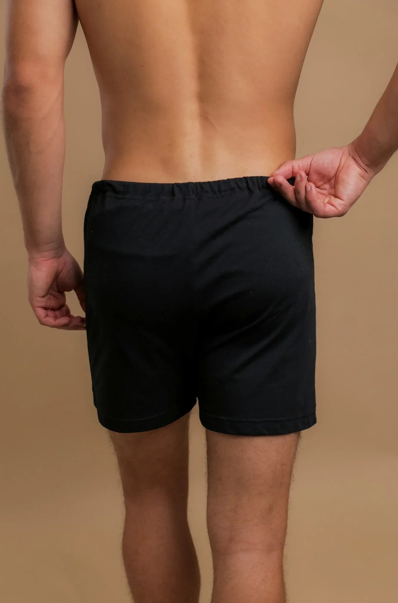 Back view of a man wearing black hypoallergenic cotton boxer shorts from Cottonique.