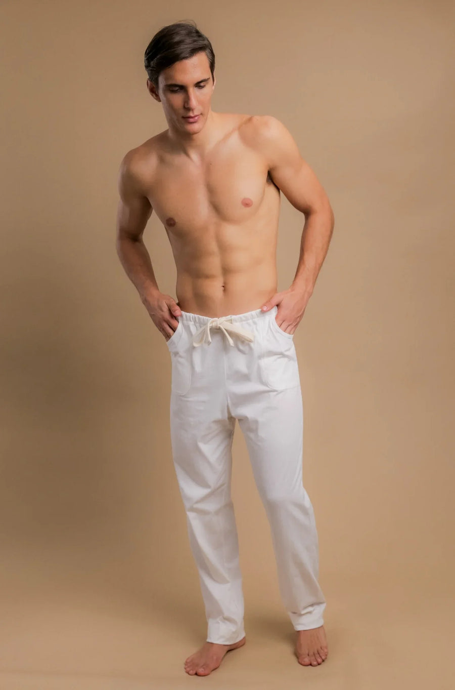 Man wearing white organic cotton drawstring pants for sensitive skin on beige background